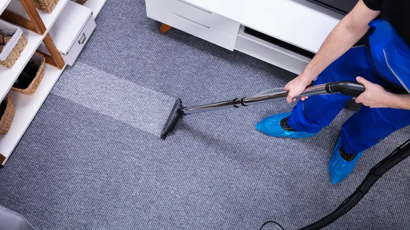 a person vacuuming carpet with a vacuum cleaner